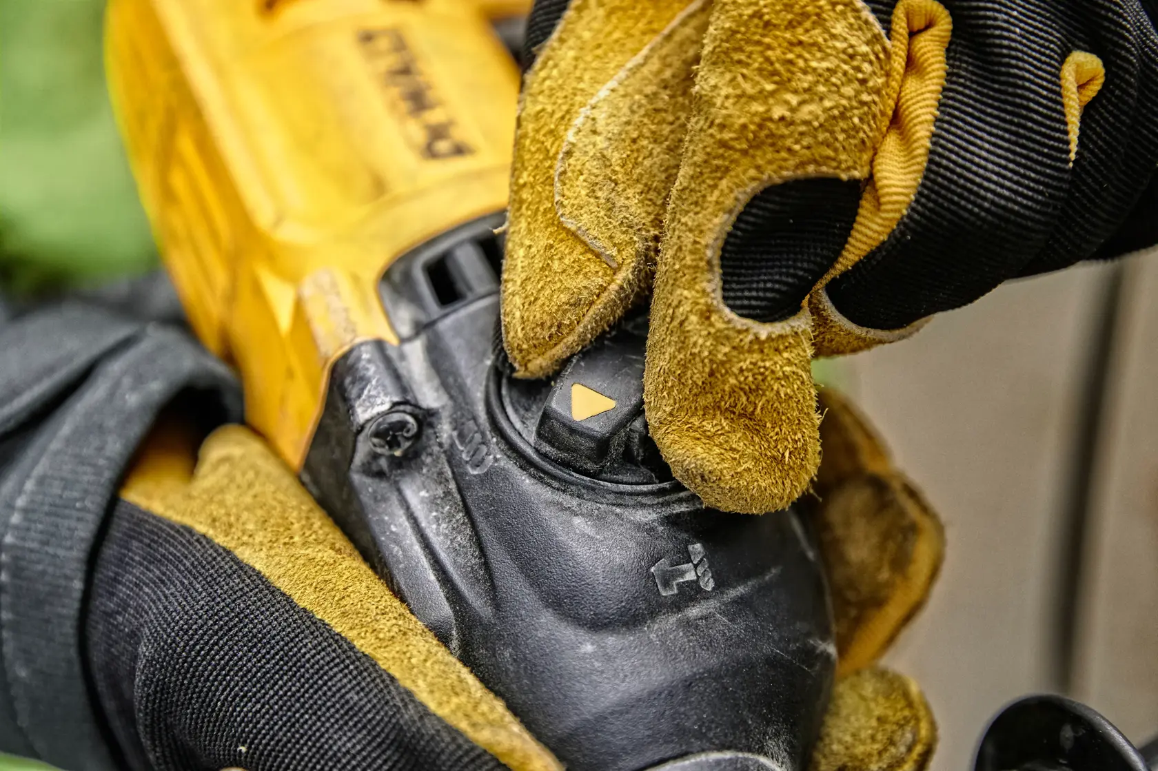 Close-up of a gloved hand adjusting the mode selector switch on a yellow DEWALT power tool.