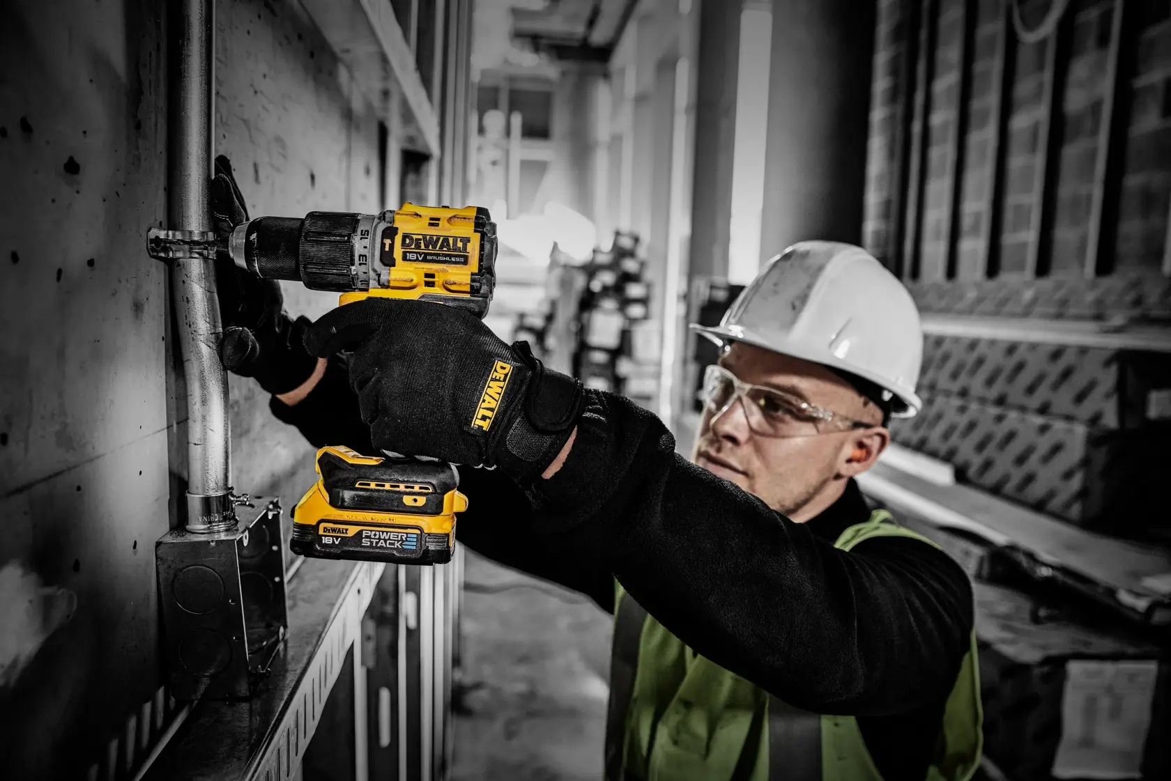Arbeiter nutzt DEWALT Powerstack-Akku mit Akkubohrer bei einer Elektroinstallation auf Baustelle.