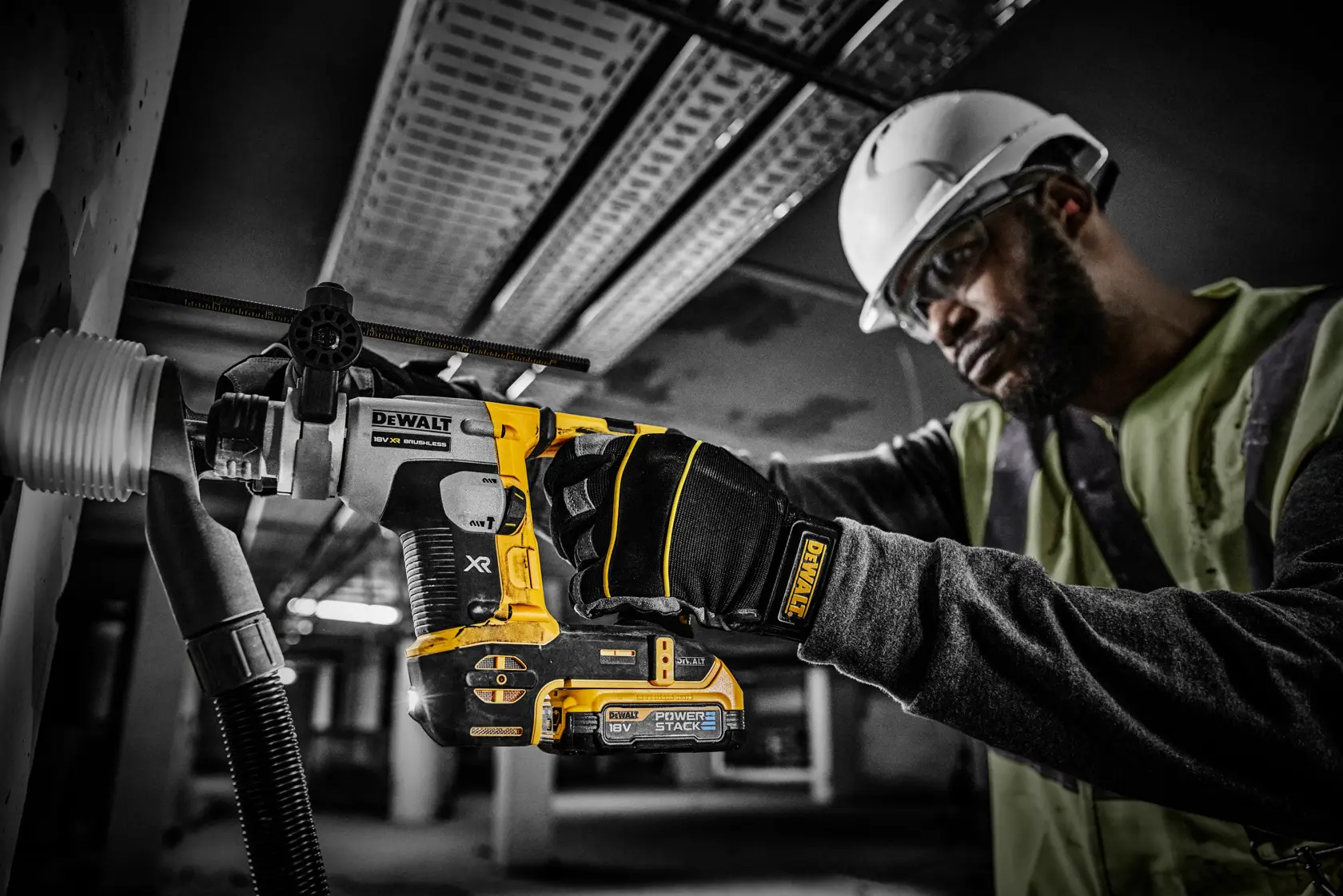 Arbeiter bohrt mit DEWALT PowerStack 18V Werkzeug in eine Wand, trägt Handschuhe und Helm.