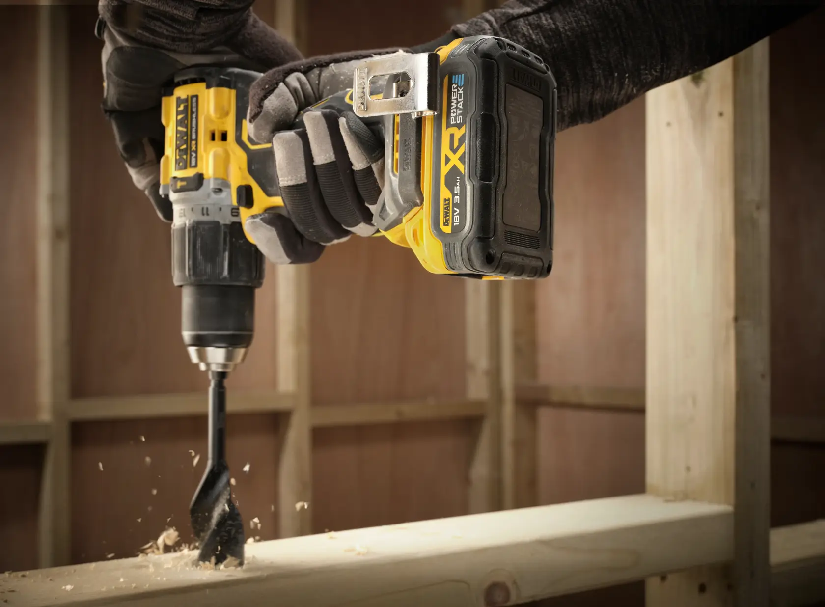 Primer plano de un taladro DEWALT con batería DCBP318 perforando madera en una obra.