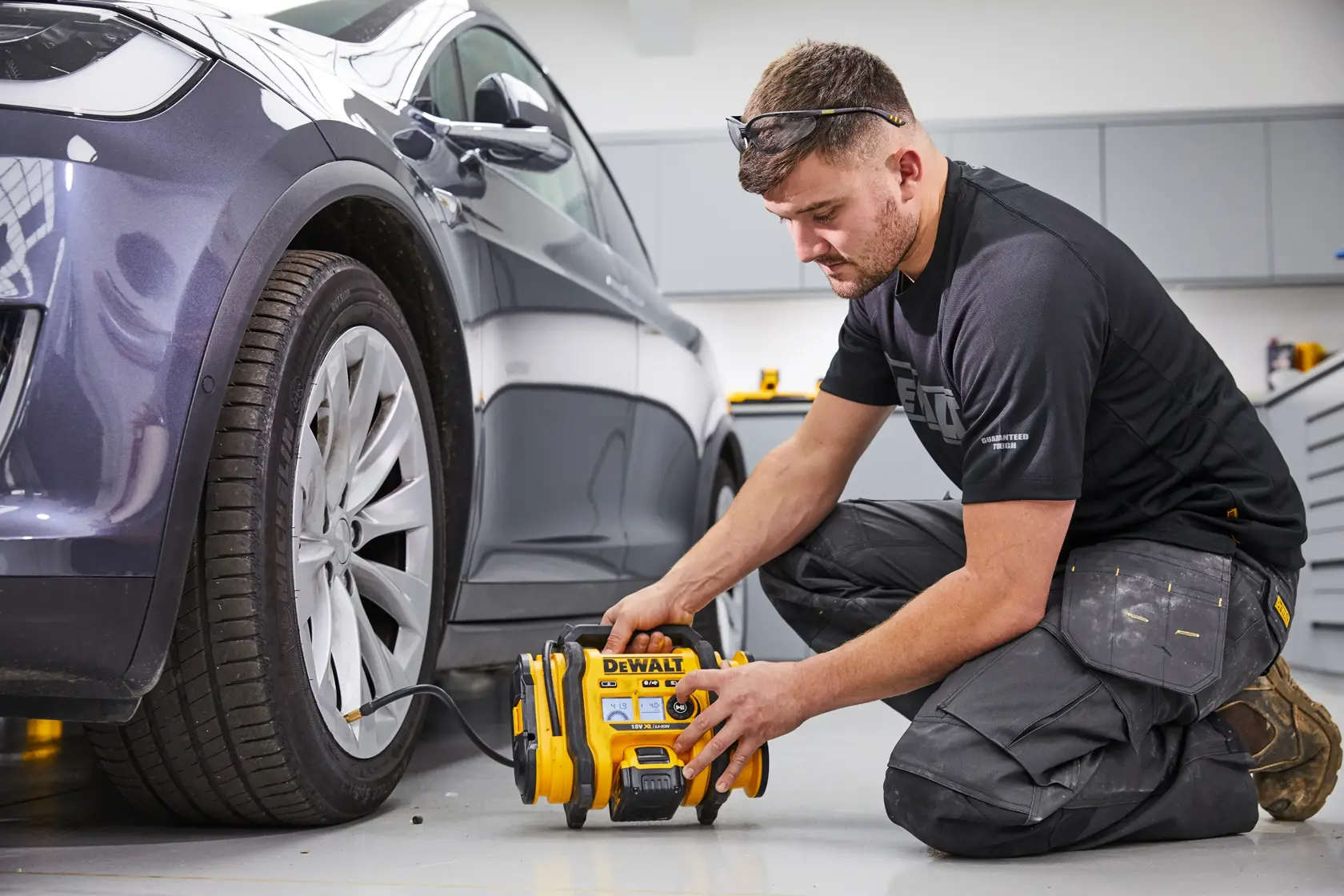 Front view of a DEWALT 18V XR Li-Ion portable air compressor with a digital display, yellow and black body, and a flexible hose attached.