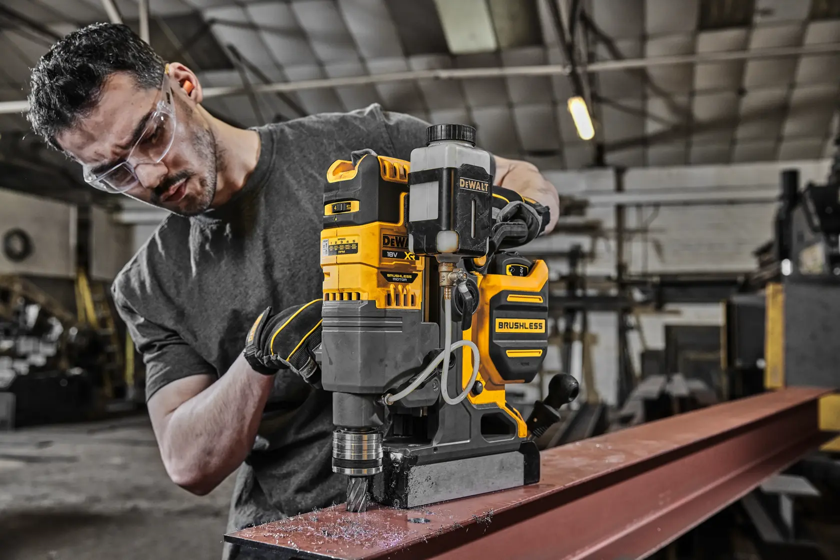 DEWALT DCD1623N Brushless-Bohrmaschine wird von Person mit verdecktem Gesicht im Werk auf Stahlträger eingesetzt.