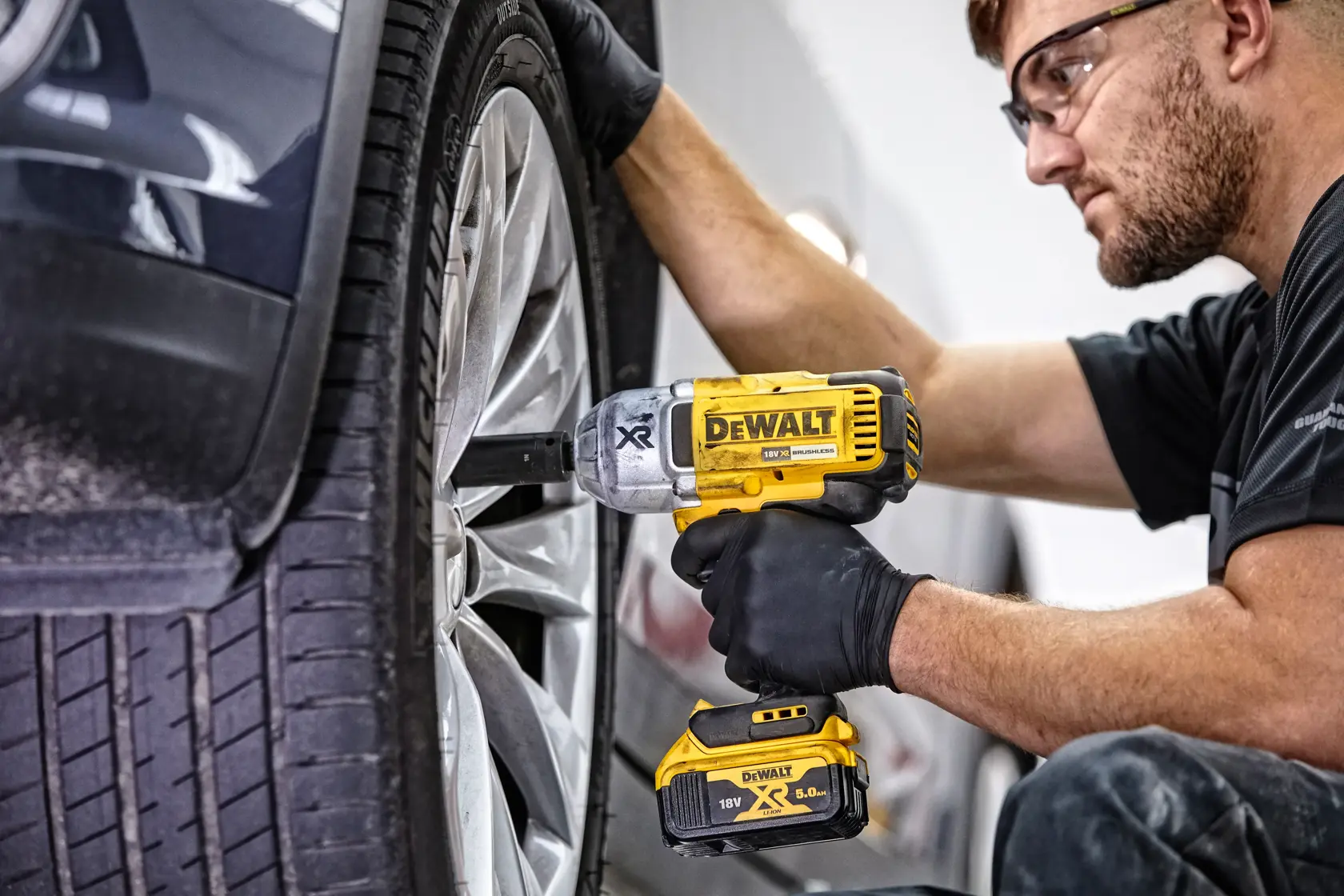 Person uses DEWALT DCF899N impact wrench to tighten a car wheel nut.