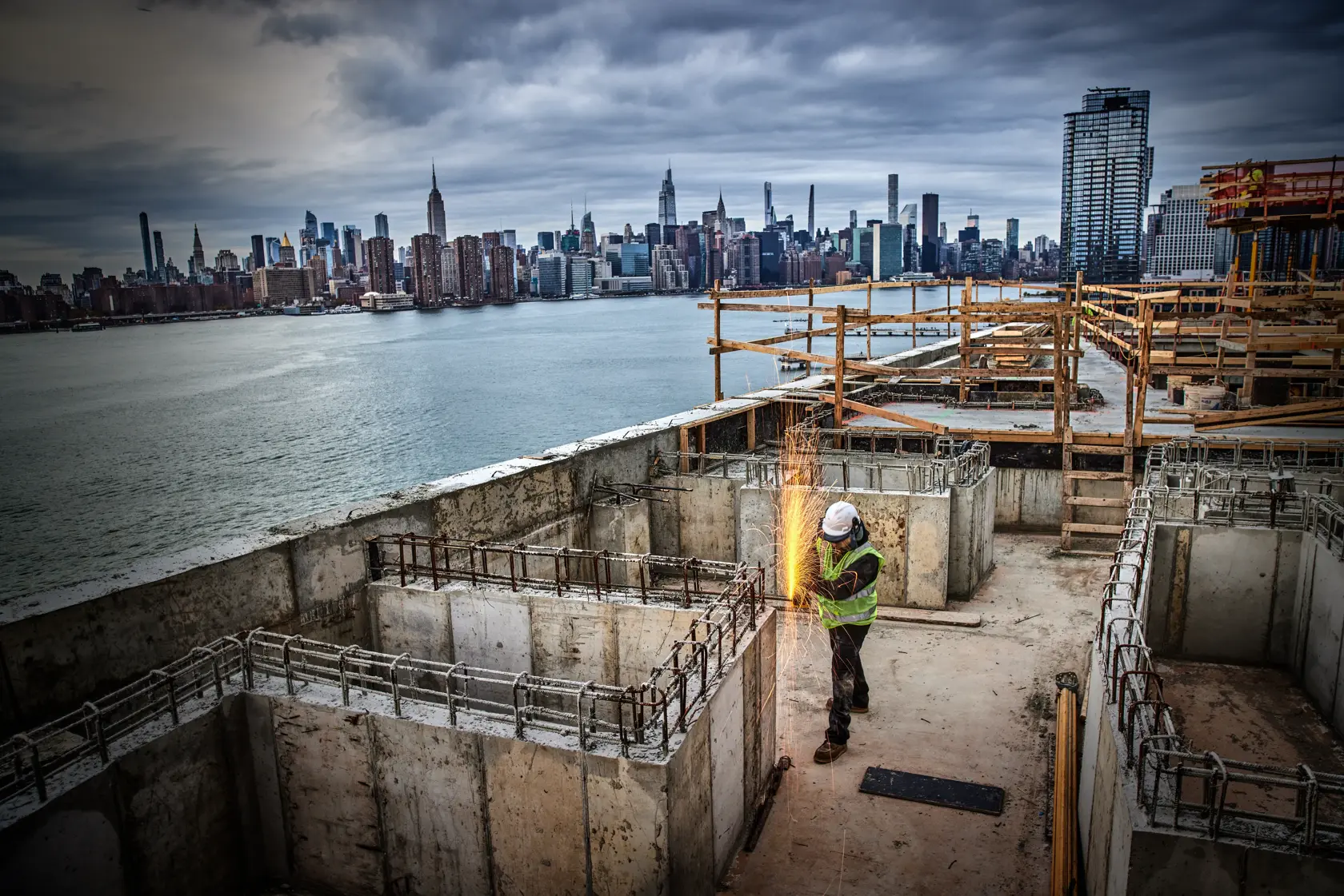 Photo of worker using DEWALT DCG405P2-IN, DCG405P2, DCG405P2-GB grinder on rooftop construction site with city skyline.