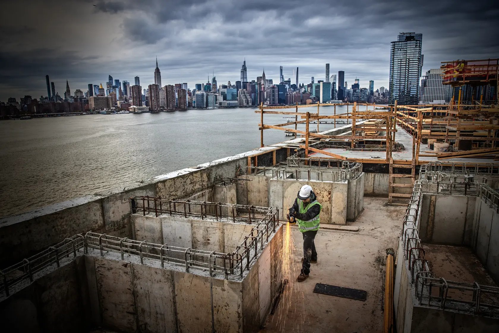 DEWALT DCG405P2-IN, DCG405P2, DCG405P2-GB grinder used on urban construction site, worker cutting metal, city skyline.