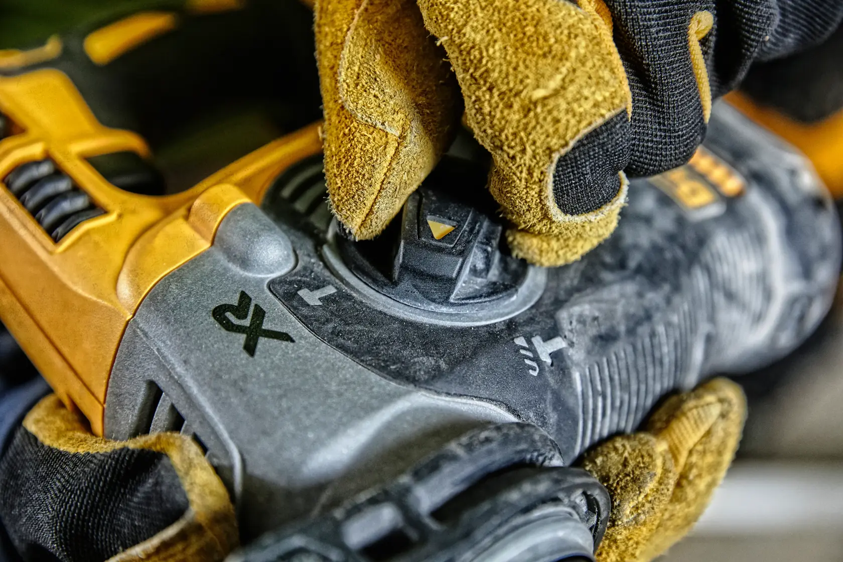 Close-up of a gloved hand adjusting the mode selector on a DEWALT DCH274P2 power tool, showing yellow and black color details.