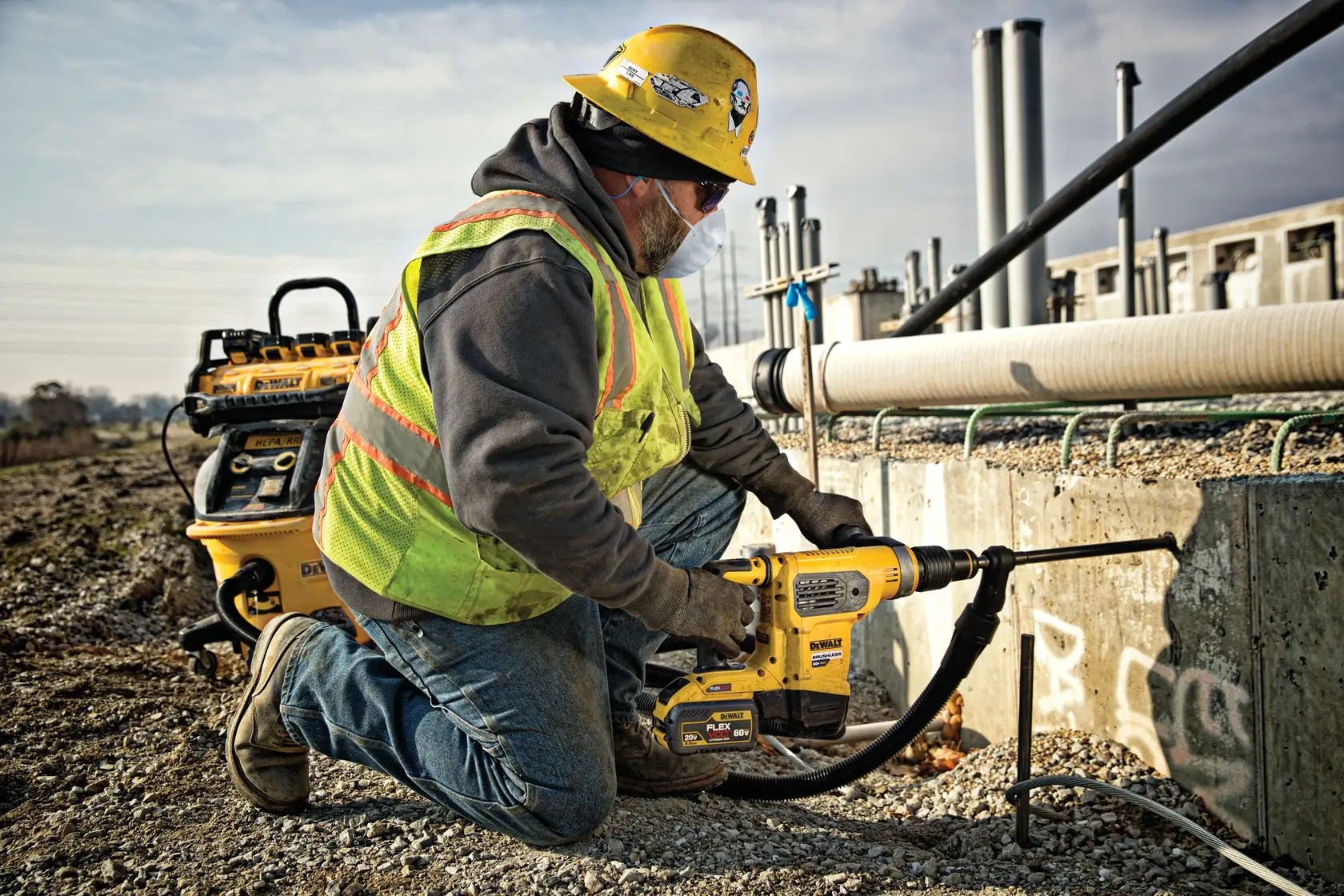 Photo of worker using DEWALT rotary hammer, SKUs DCH481X2, DCH481X2-GB, on concrete at construction site outdoors.
