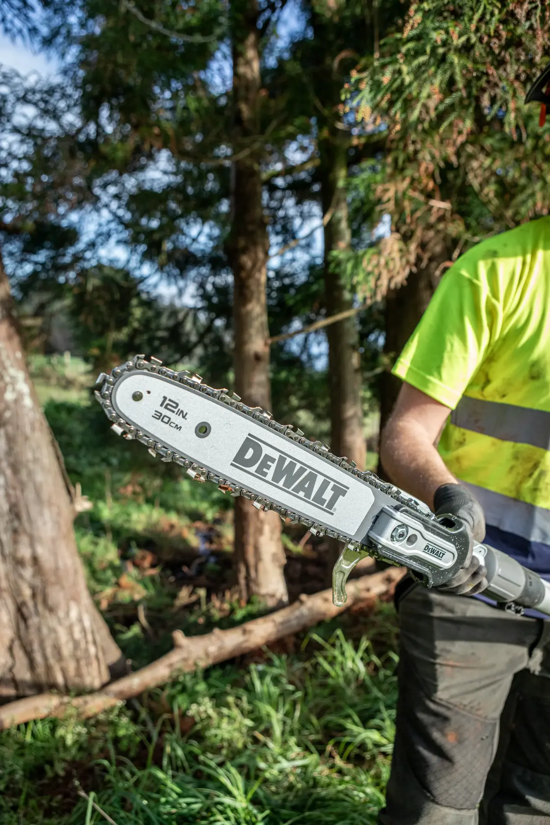 DEWALT pole saw with a 12-inch blade held outdoors by a person wearing gloves and a hi-vis shirt.
