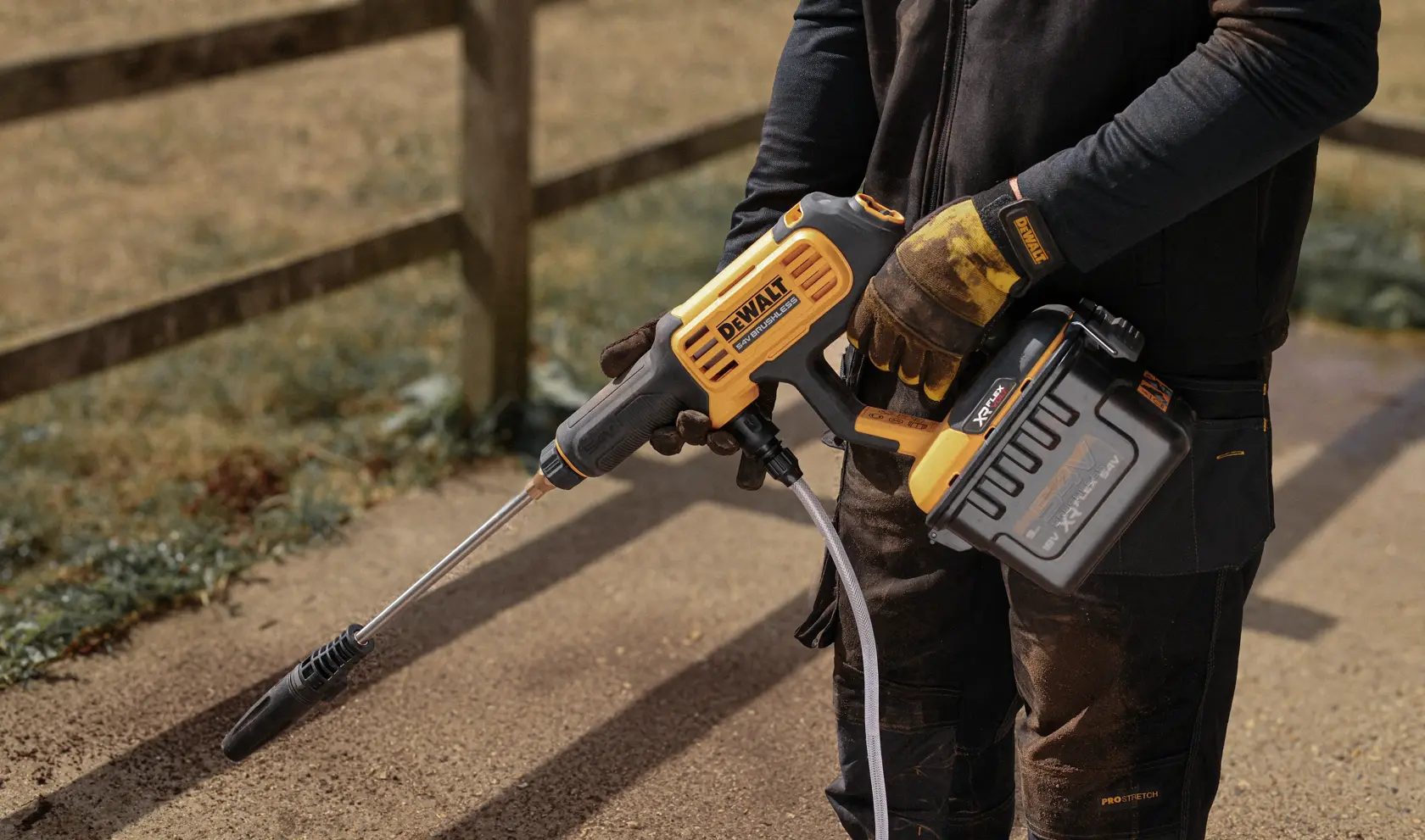 DEWALT DCMPW1000N, DCMPW1000N-XJ cordless pressure washer shown outdoors held by a person.