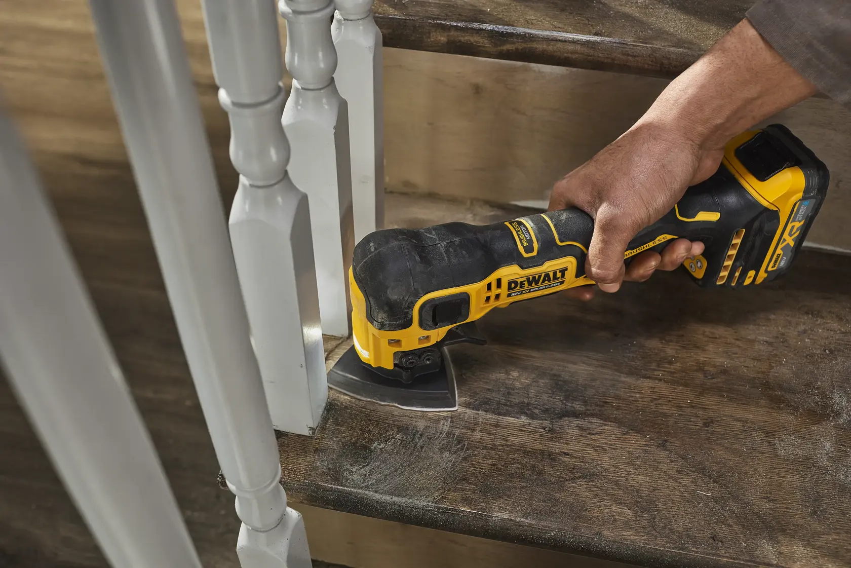 DEWALT DCS358 cordless tool sanding wooden stair near white railing.