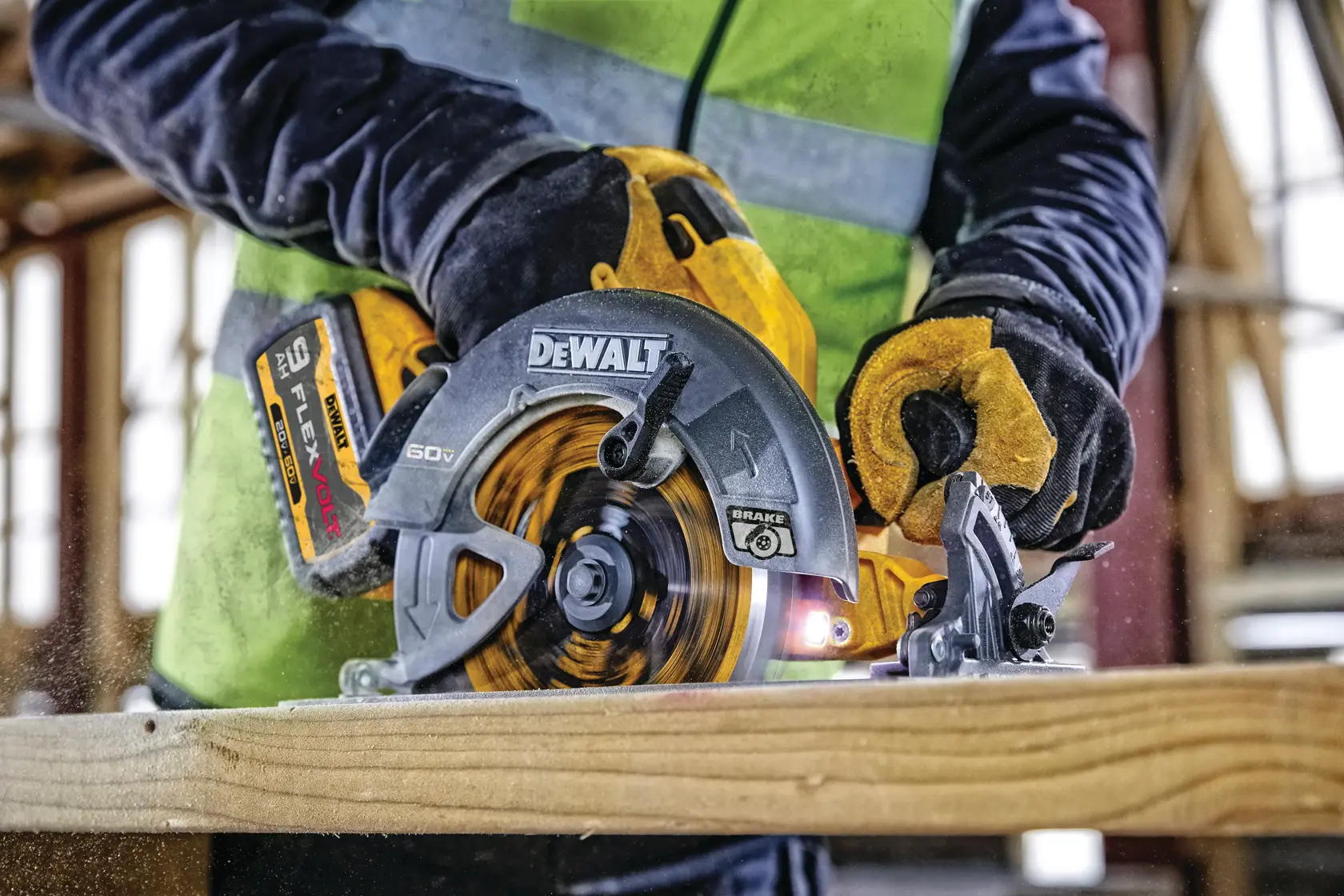 A close-up view of a person using a DEWALT DCS578X2 60V circular saw with FLEXVOLT battery to cut a wooden plank. The person is wearing safety gloves and a high-visibility vest.