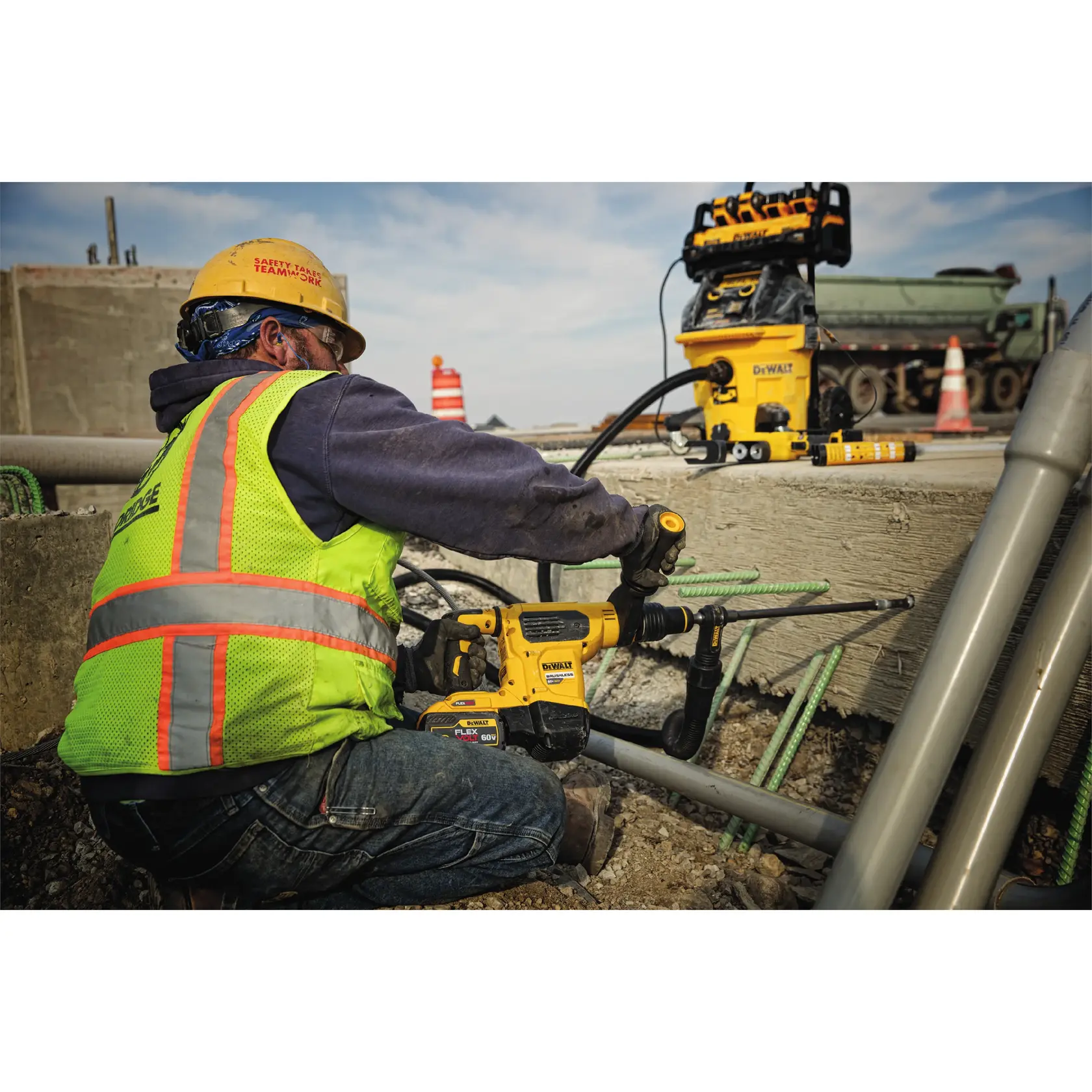 Trabajador perfora concreto con herramienta DEWALT en obra. Se ve equipo de seguridad.