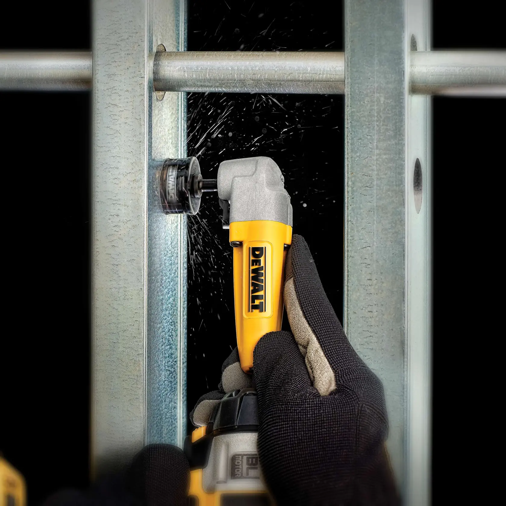 Gloved hand uses DEWALT right angle attachment to drill a hole in metal framing, producing metal shavings.
