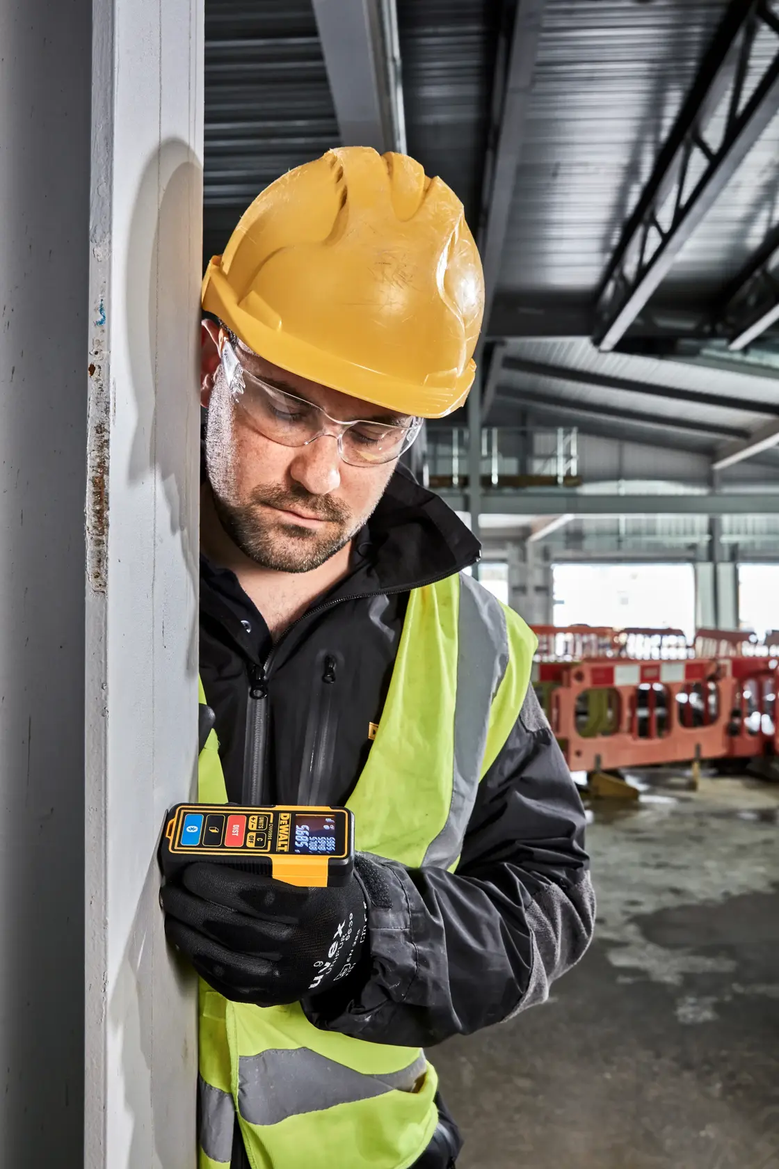 A DEWALT DW099S laser distance measurer with yellow and black casing, featuring a digital display and several control buttons on its front.