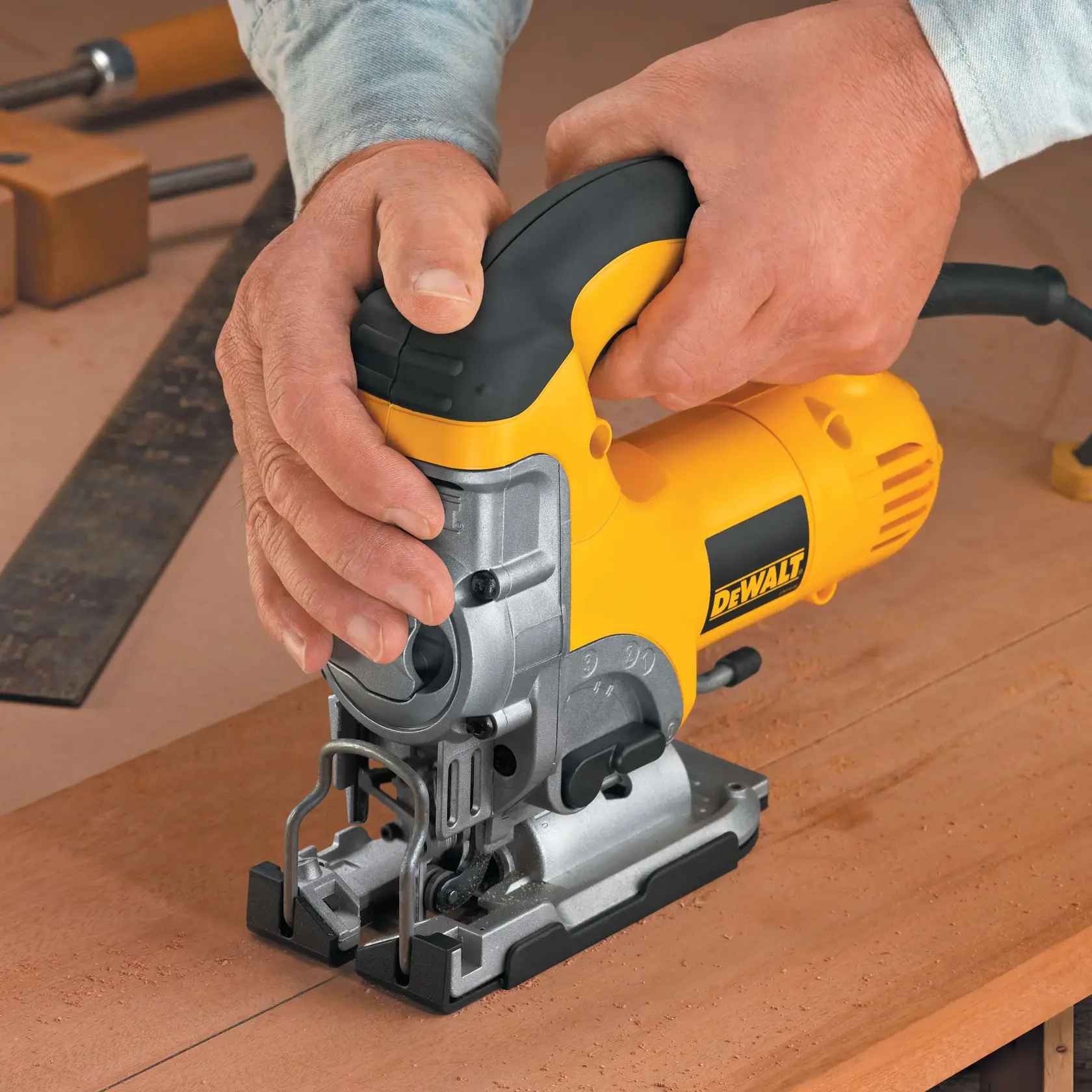 A person using a yellow and black DEWALT jigsaw (model DW331K) to cut a black material sheet.