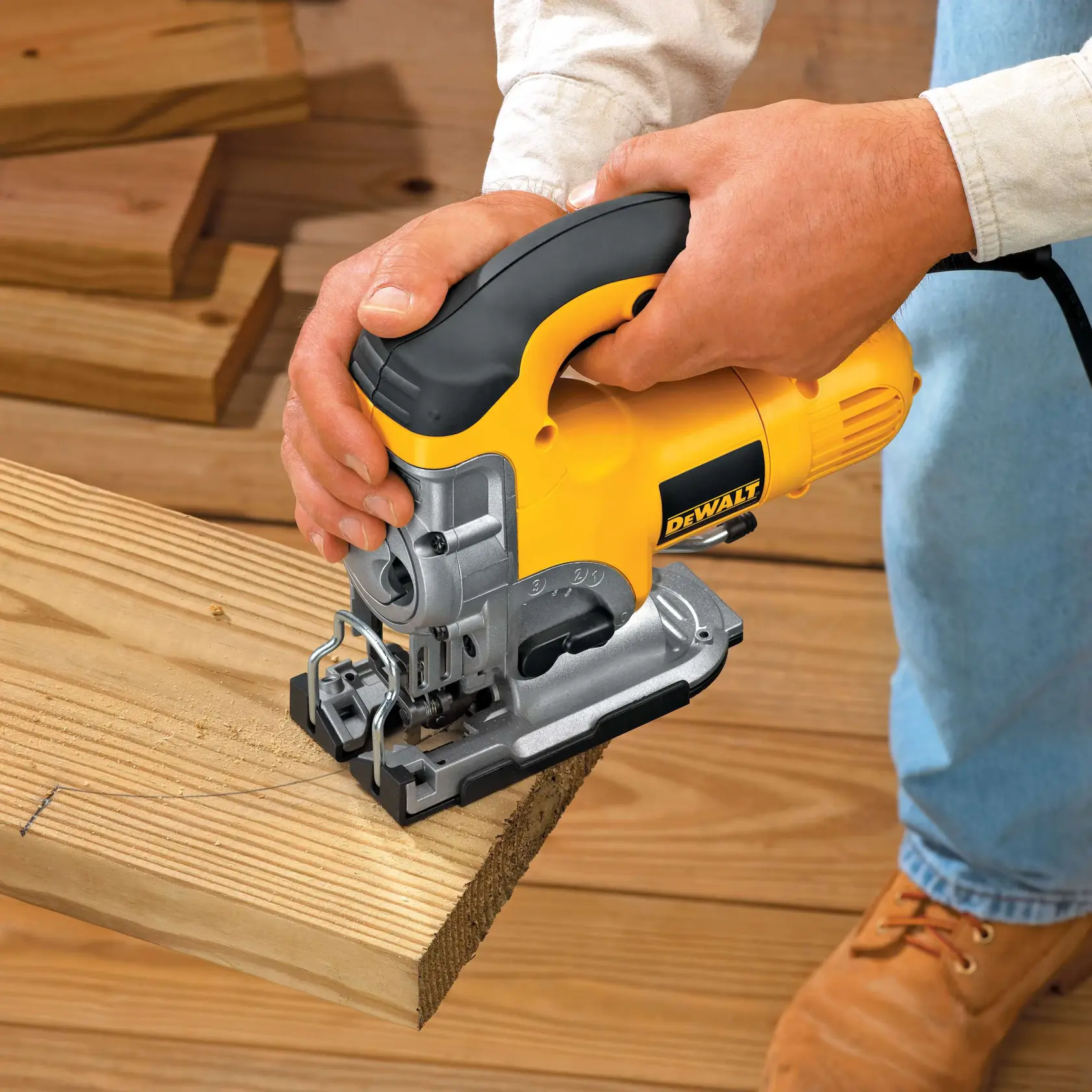 A person using a DEWALT electric jigsaw to cut a countertop. The yellow and black tool is being operated with both hands and is plugged into a power source.