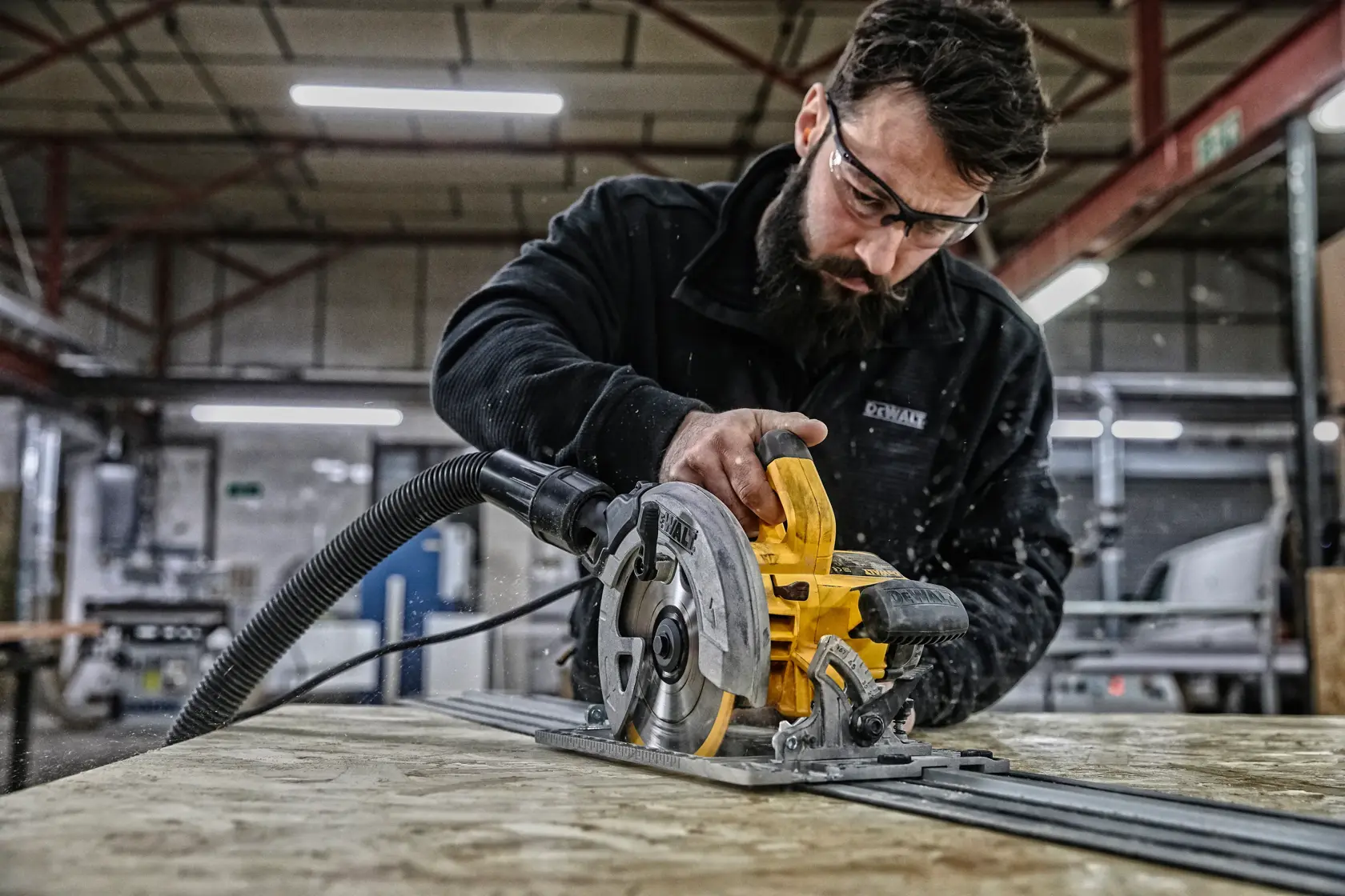 DEWALT circular saw in use on wood in a workshop, operator's face blurred for privacy.