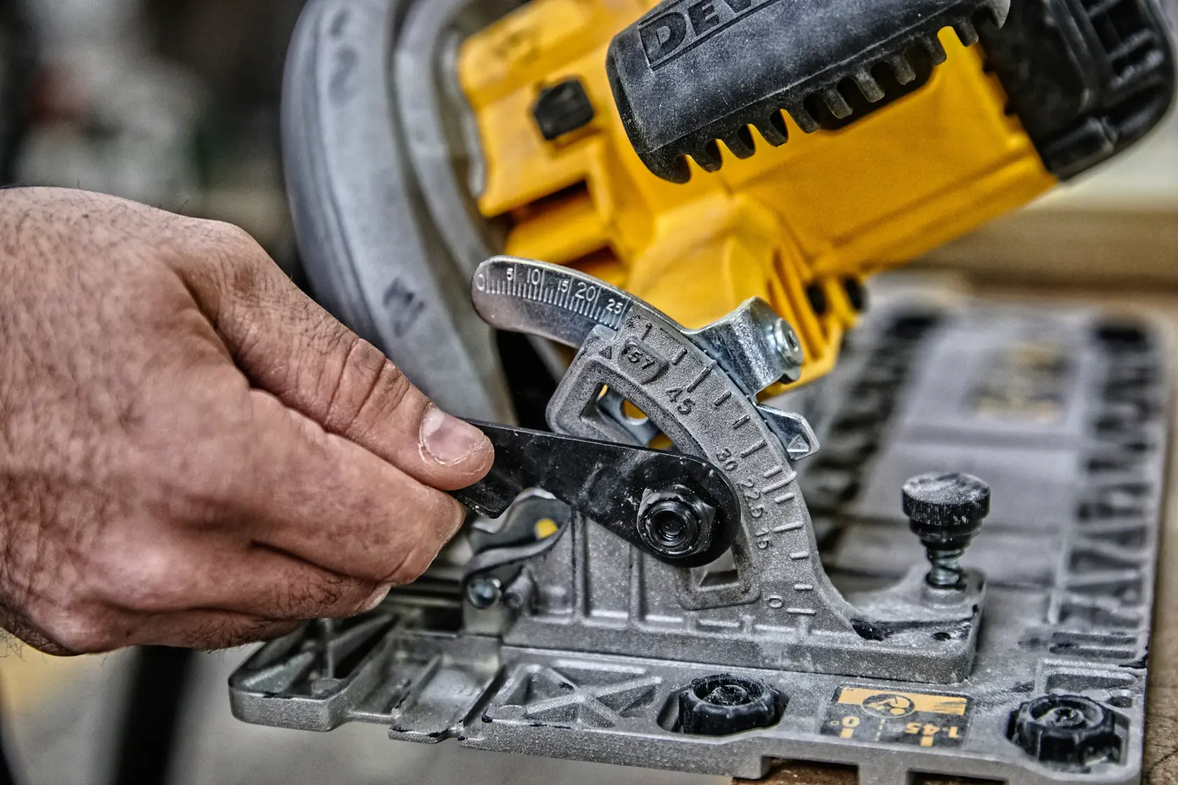 Hand adjusts angle setting on a yellow DEWALT circular saw for precise woodworking.