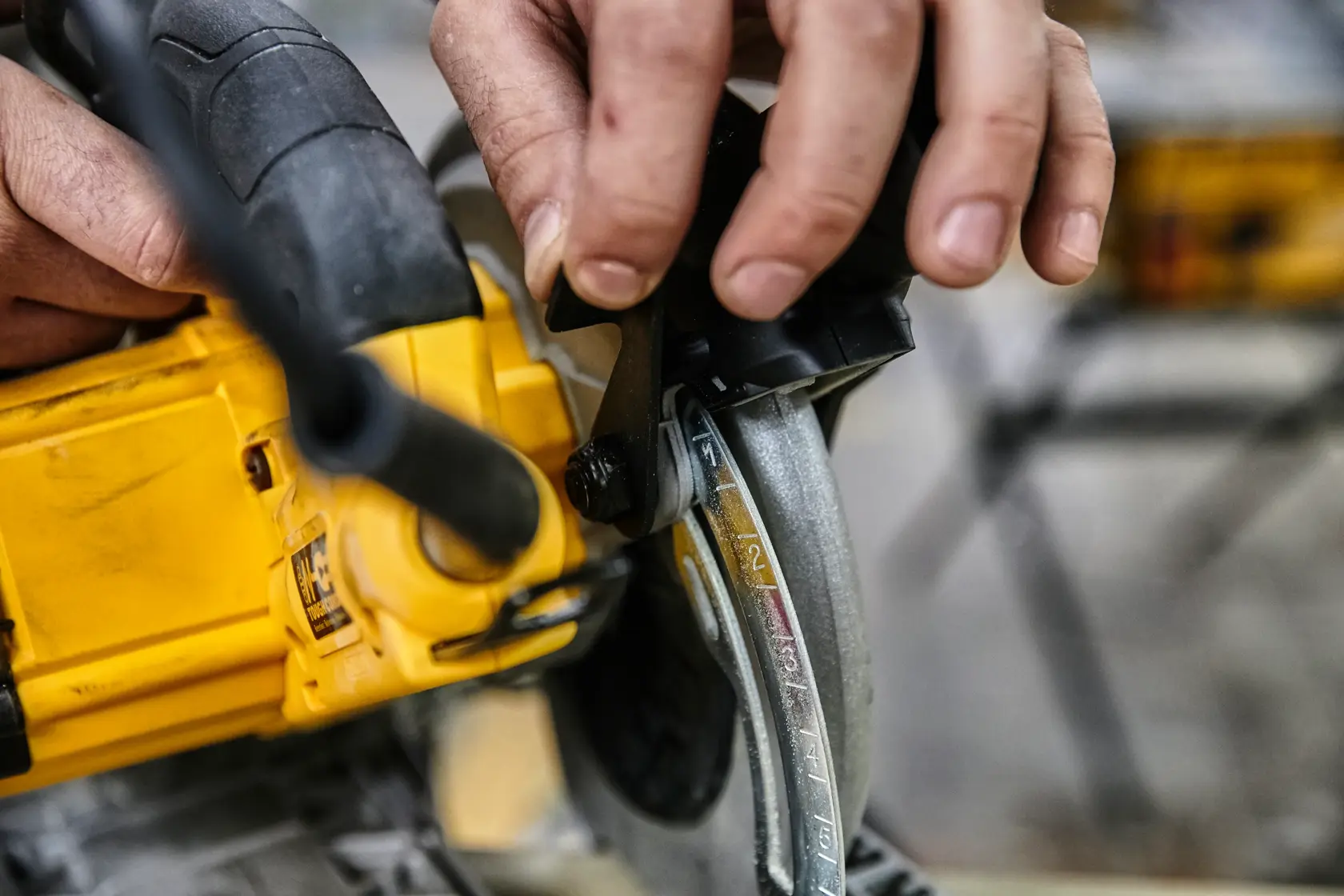 Hand adjusting the depth setting on a yellow DEWALT circular saw.