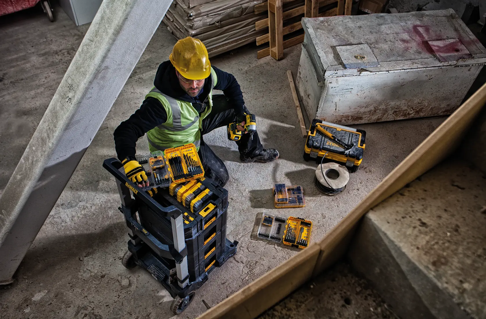 Un chariot roulant DEWALT avec une base en plastique noir, un cadre en métal argenté et quatre roues pivotantes. La plateforme comporte des mécanismes de verrouillage et une poignée relevée pour transporter des objets lourds.